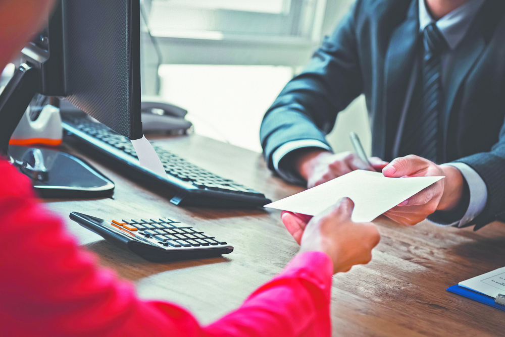 Businessman receiving money in the envelope from a woman at working desk - bribery concept