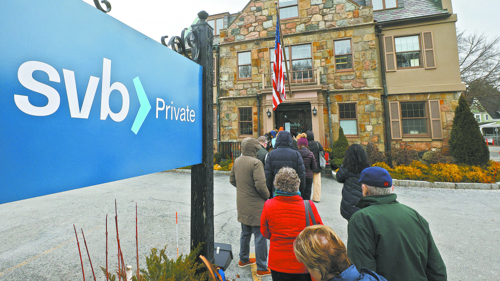 Customers wait in line outside a branch of Silicon Valley Bank in Wellesley