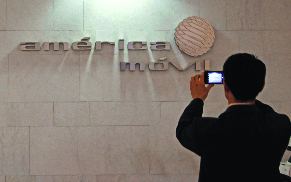 Man takes a picture of the logo of America Movil at the company