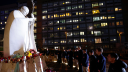 La gente reza junto a la estatua del difunto Papa Juan Pablo II en el Hospital Gemelli, donde el Papa Francisco está ingresado para recibir tratamiento de neumonía, en Roma, Italia.