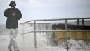 Un hombre usa su teléfono mientras las olas rompen contra la costa antes de la llegada del huracán Helene en Cedar Key, Florida.