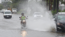 Un motociclista es sorprendido por un automovilista que circula por una calle inundada. tras el paso del huracán John en Acapulco