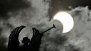 Partial view of the solar annular eclipse is pictured behind an Angels monument at the National Congress building in Buenos Aires, taken on October 2, 2024. - Part of the southern hemisphere will witness this Wednesday an annular eclipse that will occur when the Moon almost totally covers the Sun, leaving a luminous ring visible, a spectacle that will be seen in its maximum splendor from the Chilean and Argentinean Patagonia. (Photo by Luis ROBAYO / AFP)