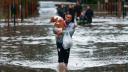 Un hombre lleva un perro mientras camina en medio de las inundaciones provocadas por las fuertes lluvias, en Capilla del Señor, en Buenos Aires.