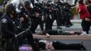 Policías antidisturbios avanzan entre manifestantes que se encuentran tendidos en la calle frente a la Oficina Local del Servicio de Ciudadanía e Inmigración de EU.