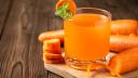Carrot juice in glass on wooden table.