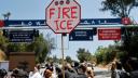 Manifestantes protestan cerca de agentes federales apostados frente a una puerta del Dodger Stadium.