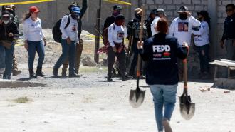 Un miembro de la Fiscalía Especializada para la Atención de Personas Desaparecidas carga palas mientras miembros del colectivo "Guerreros Buscadores" visitan el rancho Izaguirre, en Teuchitlán, Jalisco.