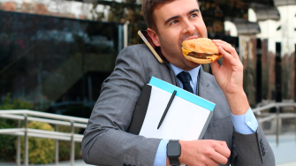 Hombre come hamburguesa.