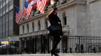 A person walks past the New York Stock Exchange (NYSE) at Wall Street on November 16, 2020 in New York City. - Wall Street stocks rose early following upbeat news on a coronavirus vaccine and merger announcements in the banking and retail industries. (Photo by Angela Weiss / AFP)