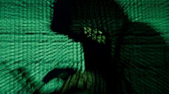 FILE PHOTO: Man holds laptop computer as cyber code is projected on him in this illustration picture