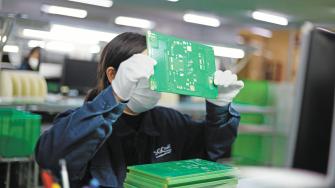 Jiujiang, China - May 26, 2021: Workers produce electronic equipment accessories such as circuit boards in a workshop of a high-tech enterprise in the economic and technological development zone.