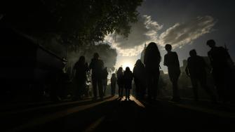 People walk on a street during the solar annular eclipse in Buenos Aires, taken on October 2, 2024. - Part of the southern hemisphere will witness this Wednesday an annular eclipse that will occur when the Moon almost totally covers the Sun, leaving a luminous ring visible, a spectacle that will be seen in its maximum splendor from the Chilean and Argentinean Patagonia. (Photo by Luis ROBAYO / AFP)