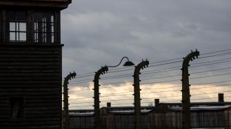 Una valla de alambre de púas y una torre de vigilancia del antiguo campo de concentración y exterminio nazi alemán Auschwitz 2-Birkenau, hoy parte del Memorial y Museo Auschwitz-Birkenau.