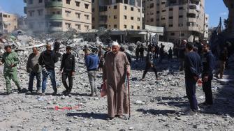 Un anciano palestino camina entre la gente reunida cerca de los escombros de la casa de la familia Elias Tarazi, tras ser destruida por un ataque israelí en el barrio de Al-Sabra, en la ciudad de Gaza.