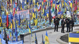 Agentes de policía montan guardia en un monumento improvisado en memoria de los combatientes ucranianos y extranjeros caídos en la Plaza de la Independencia de Kiev