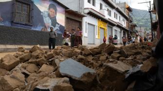 Personas caminan frente al muro derrumbado de una casa durante una serie de sismos en Santa María de Jesús, Guatemala, este 9 de julio.