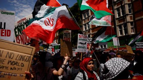 Manifestantes ondean banderas palestinas e iraníes y sostienen pancartas con la leyenda "Dejen de armar a Israel".