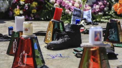 View of candles, flowers anda a shoe during a vigil in tribute to the police killed in an attack in Barranquilla, Colombia, on January 28 2018. At least three police officers were killed and fourteen other were wounded when alleged drug traffickers detonated a remote controlled bomb at a station in the northern city of Barranquilla, officials said. / AFP PHOTO