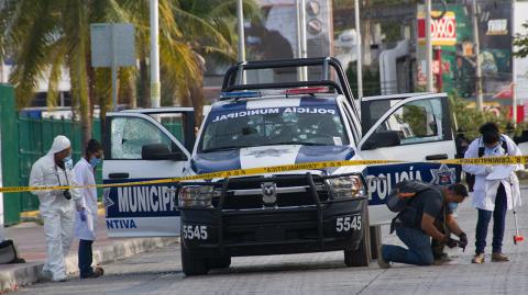 Forensic personnel and investigators collect evidence of an attack against a municipal police patrol car in Cancun, Quintana Roo state, Mexico on March 14, 2017. According to preliminary reports an indeterminate number of policemen were wounded in the attack carried out by gunmen on a motorcycle.  / AFP PHOTO / STR