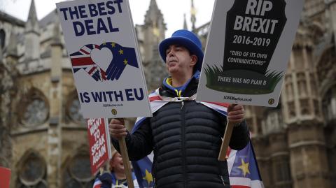 Anti-Brexit remain in the European Union supporter Steve Bray looks at his selection of double sided placards as he demonstrates opposite the Houses of Parliament in London, Monday, Jan. 21, 2019. Prime Minister Theresa May says Britain is scrapping a fee it was due to charge European Union citizens applying to settle permanently in the U.K. after Brexit. (AP Photo/Matt Dunham)