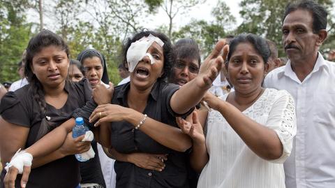 Anusha Kumari, center, weeps during a mass burial for her husband, two children and three siblings, all victims of Easter Sunday