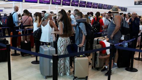 Tourists queue up in a check-in service at Cancun International Airport after Thomas Cook, the world