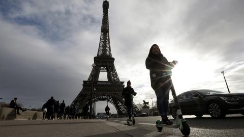 People ride dock-free electric scooters near the Eiffel tower as a strike by all unions of the Paris transport network (RATP) and French SNCF workers entered its tenth consecutive day in Pari