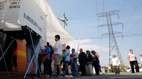 Woman prepares her ballot as other people wait in line to cast their votes at a polling station in Chimalhuacan