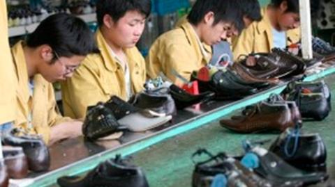 Factory workers check shoes for flaws on