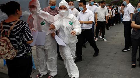 Medical workers attend to people lining up outside a site for nucleic acid tests in Beijing