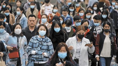 People wearing face masks walk on a street, following a sandstorm in Shanghai