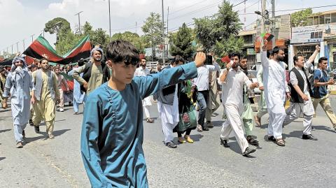 People carry the national flag at a protest held during the Afghan Independence Day in Kabul