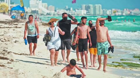 Tourists walk  along a beach as the coronavirus disease (COVID-19) pandemic continues, in Cancun, Mexico January 6, 2022. REUTERS/Paola Chiomante NO RESALES. NO ARCHIVES-NARCH/NARCH30