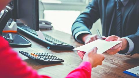 Businessman receiving money in the envelope from a woman at working desk - bribery concept