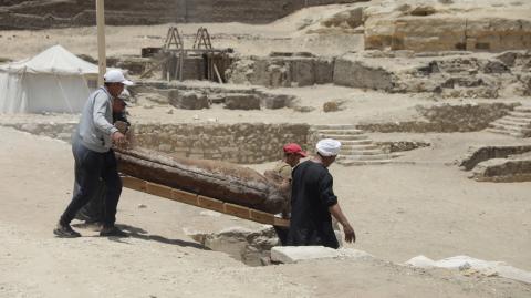 Workers carry a sarcophagus from newly discovered burial site, in Giza