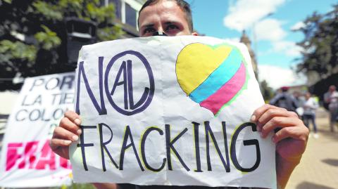 FILE PHOTO: A man holds a sign that reads: "No to fracking", during a protest against the use of fracking, in Bogota