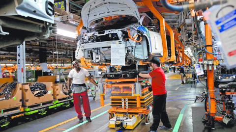 FILE PHOTO: General Motors assembly workers connect a battery pack underneath a partially assembled Chevrolet Bolt EV vehicle