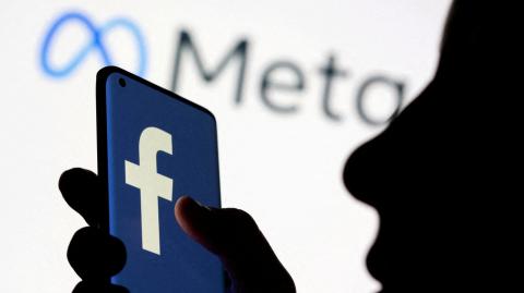 FILE PHOTO: A woman holds smartphone with Facebook logo in front of a displayed Facebook's new rebrand logo Meta in this illustration picture taken October 28, 2021. REUTERS/Dado Ruvic/Illustration/File Photo-NARCH/NARCH30 NARCH/NARCH30 NARCH/NARCH30 NARCH/NARCH30 NARCH/NARCH30