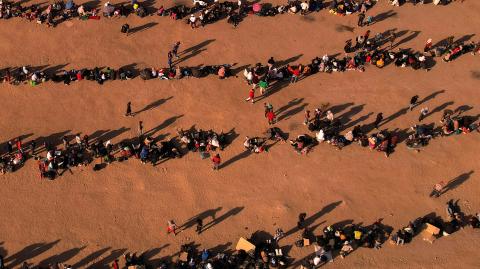 Migrants stand near the border wall, as seen from Ciudad Juarez