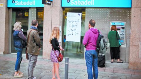 People line up at a Sabadell Bank ATM machine in Barcelona to withdraw money as part of an action to protest the transfer of the bank's headquarters out of Barcelona, Spain, October 20, 2017. REUTERS/Ivan Alvarado