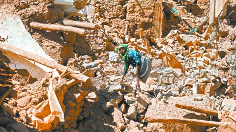 Una mujer camina sobre los escombros intentando rescatar a su cabra tras el terremoto. Foto: Reuters