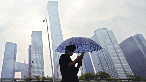 FILE PHOTO: A man walks in the Central Business District on a rainy day, in Beijing