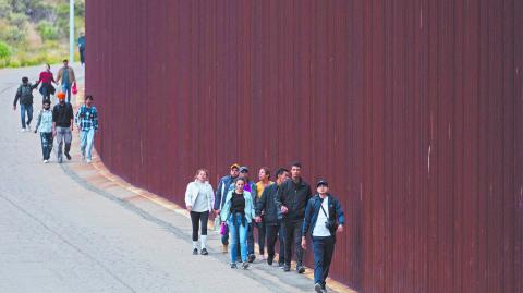 Solicitantes de asilo caminan entre dos muros fronterizos al cruzar desde San Diego. Foto: Reuters