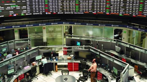 Employees work at their positions as a ticker displays stock exchange data at Mexico