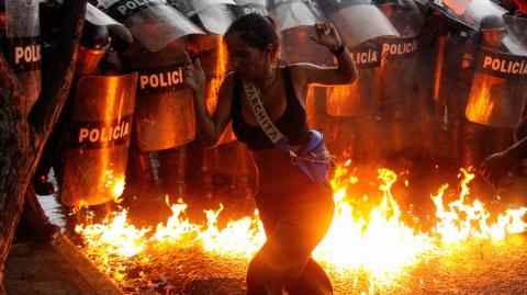 Un manifestante reacciona cuando bombas molotov caen al suelo frente a las fuerzas de seguridad durante las protestas contra los resultados electorales en Venezula. Foto: Reuters