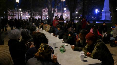 Personas comen alimentos proporcionados por la organización Red Solidaria en la Plaza de Mayo, frente al palacio presidencial de Casa Rosada en Buenos Aires, capital argentina.