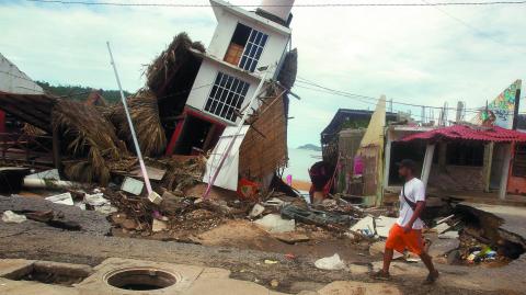 A man walks near a damaged building after the passing of Tropical Storm John, in Puerto Marques, Guerrero state, Mexico September 29, 2024. REUTERS/Javier Verdin