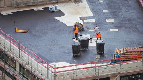 Roofer painting flat roof of a commercial building.