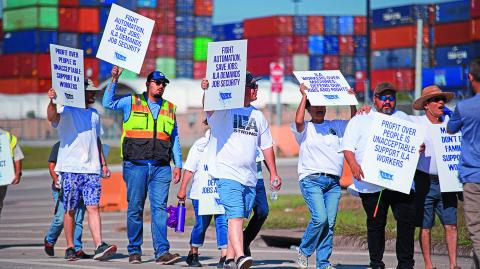 Striking workers hold up signs and march in front of the Bayport Container Terminal in Seabrook, Texas, on October 3, 2024. - The International Longshoremen's Association (ILA), 85,000 members strong, has launched its first strike since 1977 after weeks of deadlocked negotiations over a six-year labor agreement. (Photo by Mark Felix / AFP)